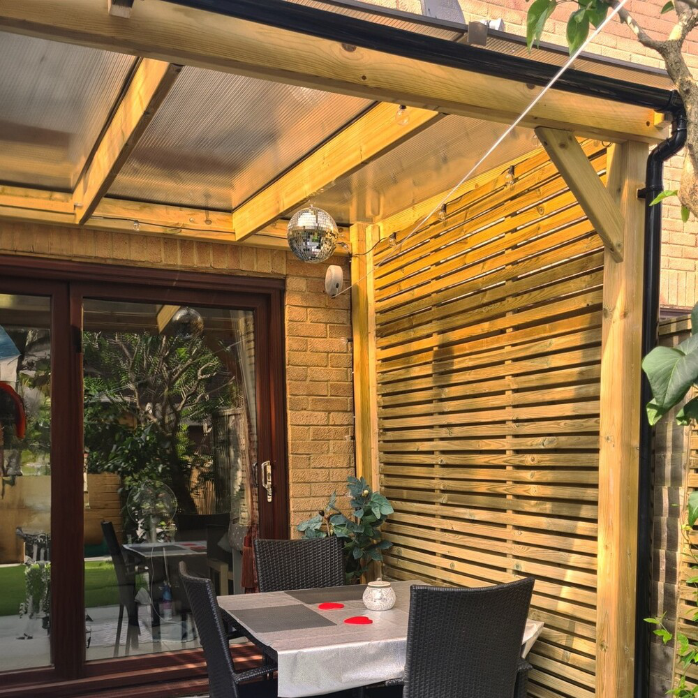 Outdoor patio area with wooden gazebo, table, and chairs.